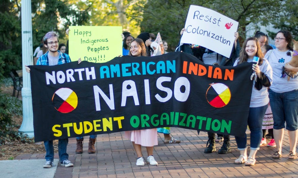 <p>Issac Ward, Tori Ottinger and Jillian Mutchler (left to right) hold up a banner as they march on Oct. 9, from the Beaumont Tower to the Rock on Farm Lane. The march led to an event at the Rock in celebration of Indigenous Peoples&#x27; Day.</p>