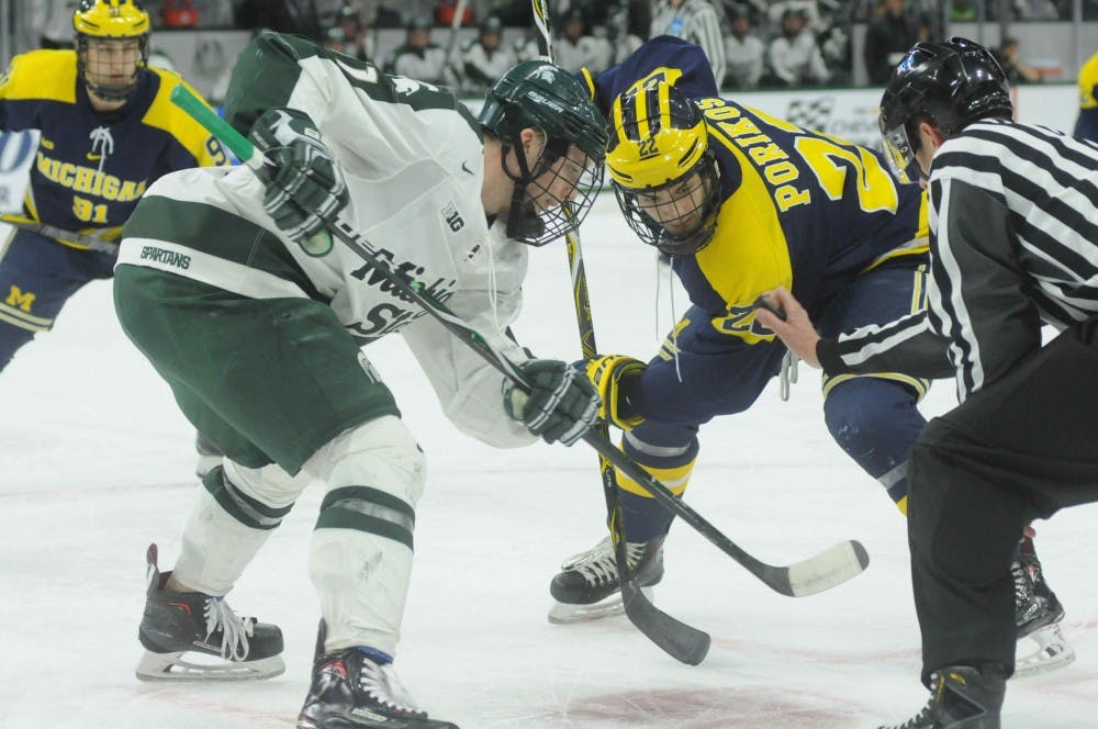 Michigan's senior left wing Niko Porikos (22) faces off against  freshman center Tommy Apap (11) during the game against Michigan on Feb. 9, 2018 at Munn Ice Arena. The Spartans and Wolverines tied 1-1, but the Spartans lost in a shootout.(Annie Barker | State News)