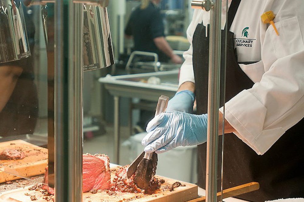 <p><span style="color: rgb(33, 33, 33);">East Lansing resident and MSU employee John Delgado slices meat for a student Jan. 12, 2015, during lunch time at the new Akers Dining Hall. The dining hall was added as part of recent renovations to the Akers complex.</span></p>