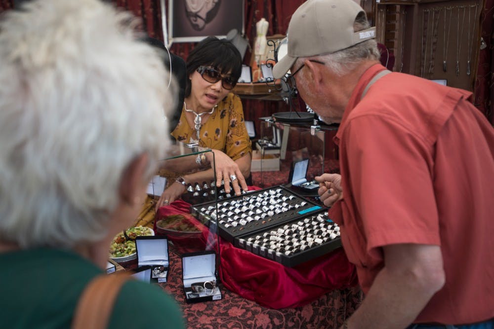 Thousand Oaks, Calif. artist Pam Amputh shows her display of jewelry to Harbor Beach, Mich. residents Len Gajewski, right, and Mary Ann Gajewski during the 53rd annual East Lansing Art Festival on May 22, 2016 in East Lansing. The East Lansing Art Festival is ranked 50th in the nation in the Top 100 Fine Art Festival List by Sunshine Artist Magazine.