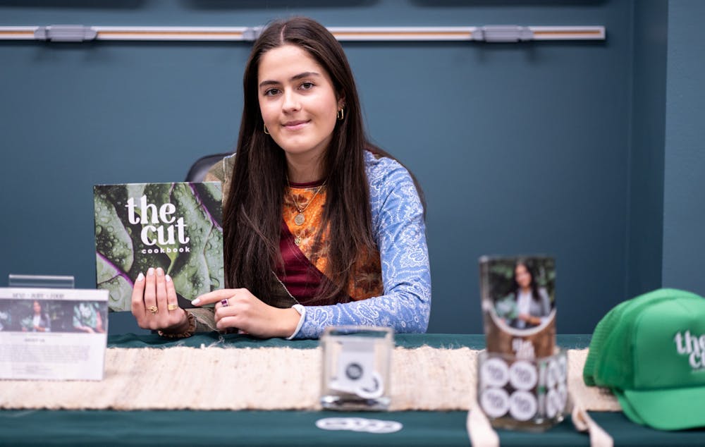 Environmental Economics and Management senior Madison Marsh poses with her cookbook "The Cut" during a shop start-ups and explore entrepreneurship event in the Student Services building on Dec. 2, 2022. 