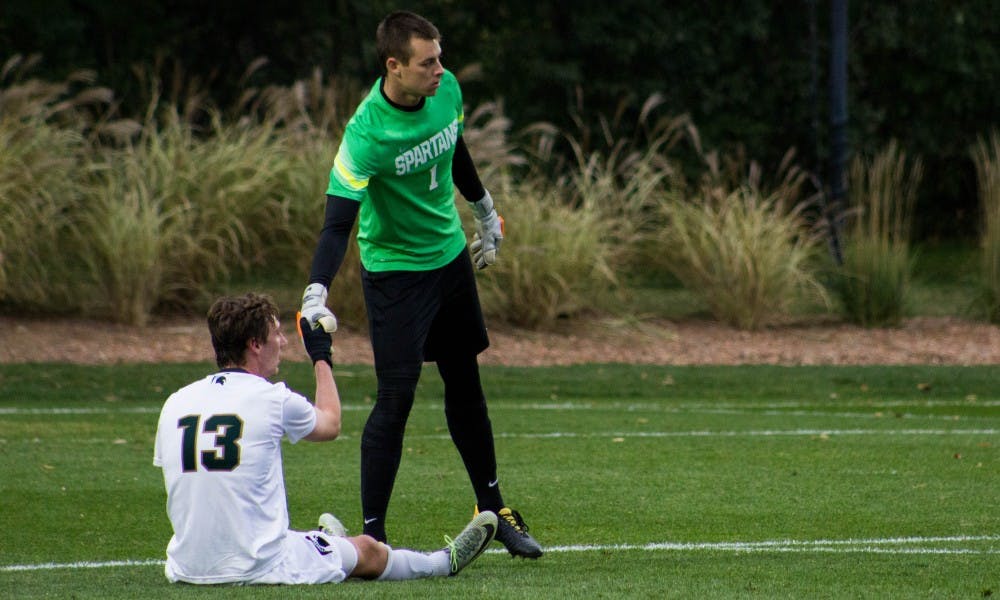 Red shirt junior goalkeeper Jimmy Hague (1) helps junior midfielder Robbie Cort (13) to his feet during the game against Indiana on Oct. 29, 2017, at DeMartin Stadium. The Spartans and the Hoosiers tied 1-1 in double overtime.