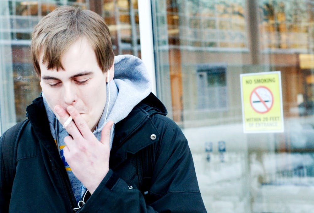 Nutrition junior Jake Miller smokes Wednesday afternoon outside Main Library. Residence Halls Association, or RHA, is looking to formulate a committee to address smoking rules outside university buildings. Justin Wan/The State News