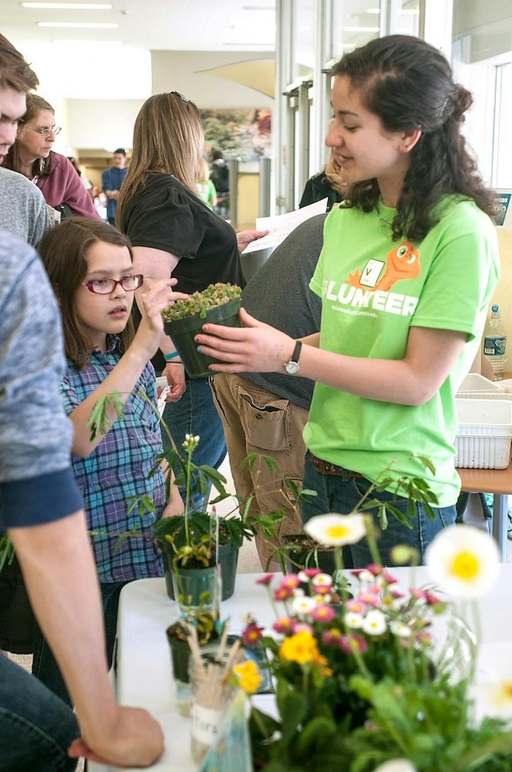 <p>Plant biology senior Elena Michel holds a plant for Williamston resident Lauren Schafer, 8, to touch April 18, 2015, during the MSU Science Festival in the Chemistry building. Michel is a member of the Plant Biology Club which had an educational booth at the event. Kelsey Feldpausch/The State News</p>