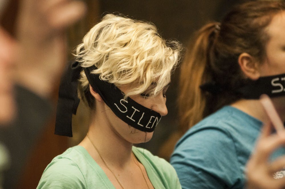 Survivor Amanda Thomashow covers her mouth in cloth that reads "silenced" during the Board of Trustees meeting on April 13, 2018 at Hannah Administration Building. (C.J. Weiss | The State News)