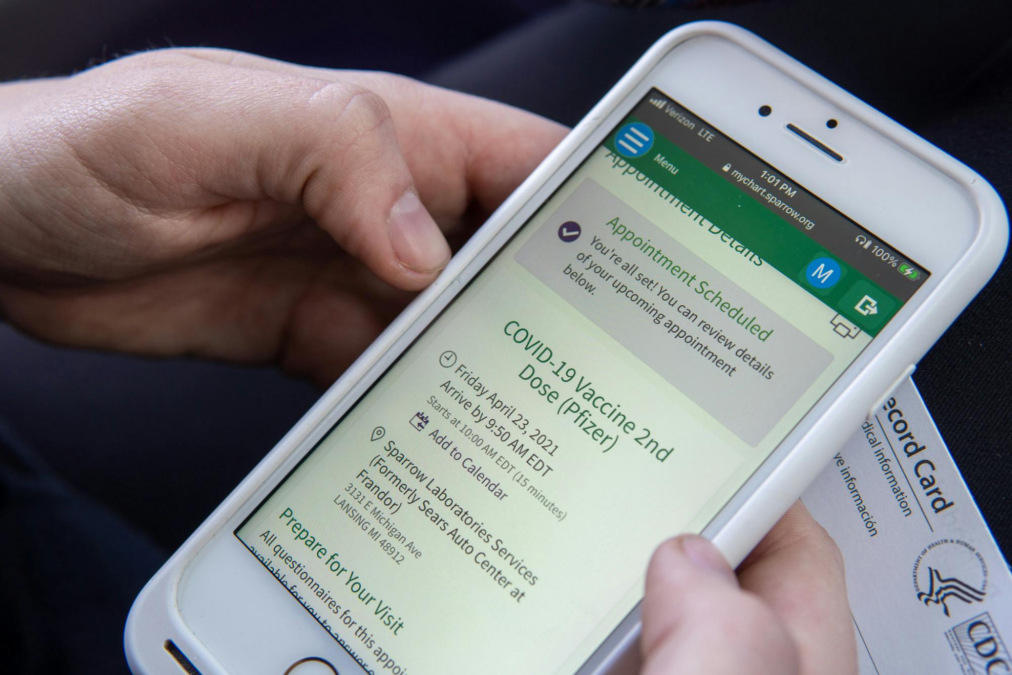 Michigan State student Maddie Monroe sets an appointment to get the second dose of the COVID-19 vaccine on her phone, while waiting to leave Sparrow Laboratories Sears vaccine location on Mar. 29, 2021.