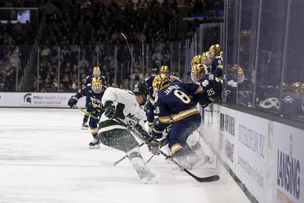 <p>Michigan State University graduate defender Nicklas Andrews (27) and Notre Dame graduate forward Grant Silianoff (9) kick up ice as they skate after the puck at Munn Ice Arena on Nov. 16, 2024. MSU defeated Notre Dame 4-3.</p>