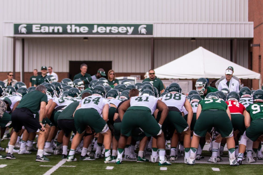 <p>The offensive and defensive squads huddle up before their practice on Aug. 2, 2018 at Duffy Daugherty Football Building.</p>