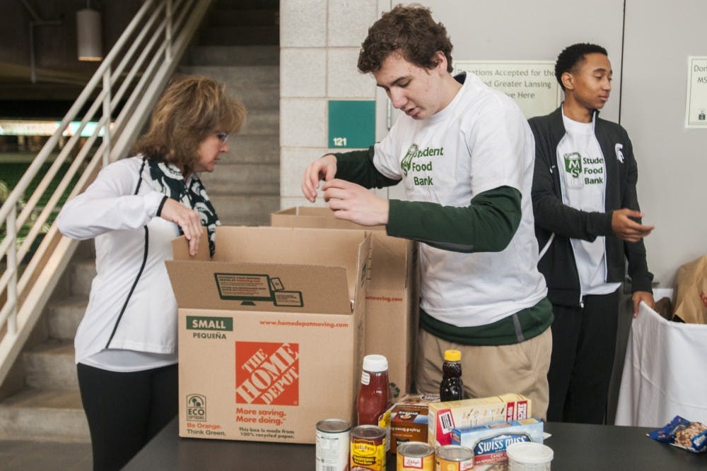 East Lansing resident Lisa Bres, left, and East Lansing resident Max Kuhnert, 15, right, put donated food in a box during the MSU Rebounders Club Annual Food Drive on Jan. 29, 2017 at Breslin Center. Bres is good friends with Lupe Izzo who has planned this event in coordination with the MSU Student Food Bank for 23 years. The proceeds and food raised from the fundraiser will be split evenly between the MSU Student Food Bank and Greater Lansing Food Bank. 