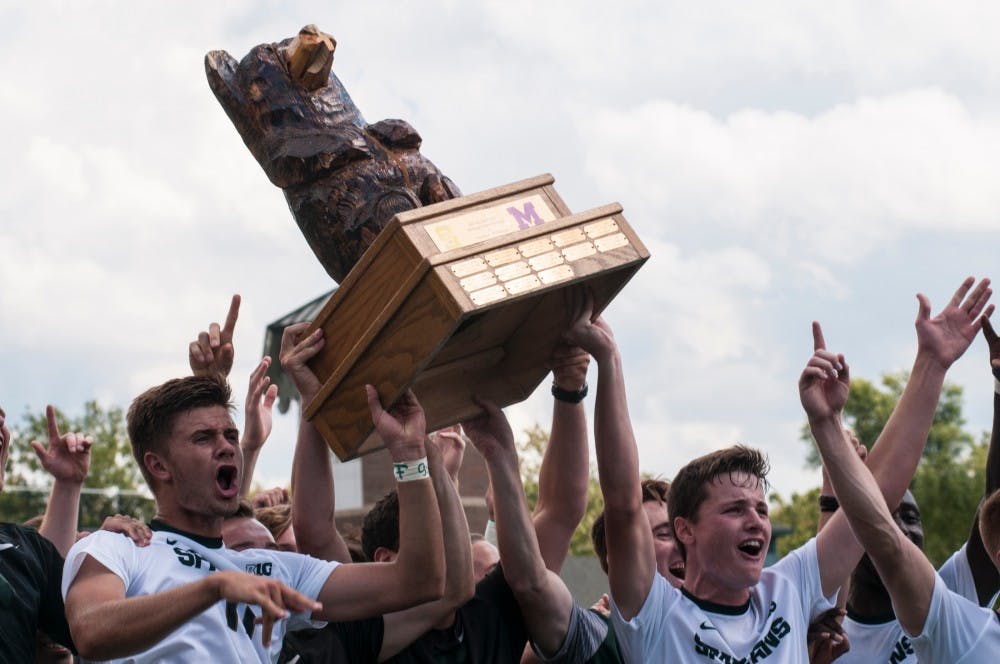 Sophomore forward Ryan Sierakowski, left, and Junior defender Brad Centala, right, celebrate with the Big Bear Trophy alongside their teammates on Sept. 18, 2016 at DeMartin Stadium at Old College Field. The Spartans defeated the Michigan Wolverines, 1-0, earning bragging rights and possession of the trophy for the year. 