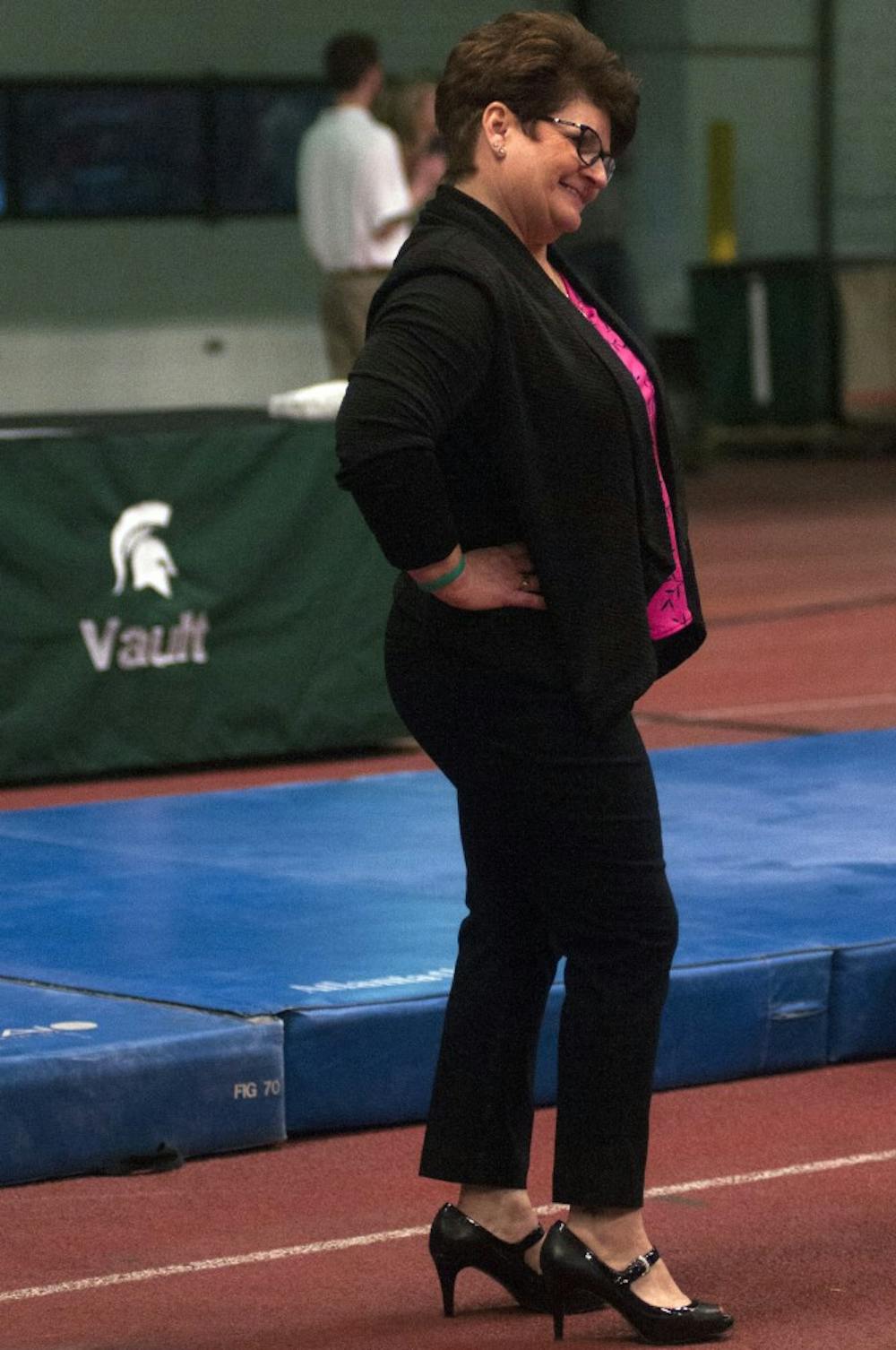 Head coach Kathie Klages smiles to her team Jan. 24, 2015, during the Breast Cancer Awareness Meet against Minnesota at Jenison Fieldhouse. The gymnastics team lost with a score of 196.875-195.750. Hannah Levy/The State News
