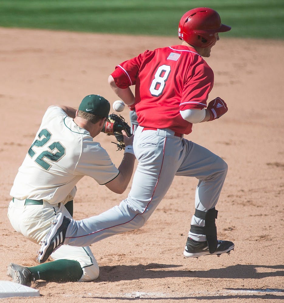 <p>Junior first baseman Ryan Krill drops a ball as Nebraska catcher Tanner Lubach crosses first base May 10, 2014, at McLane Baseball Stadium at Old College Field. The Cornhuskers defeated the Spartans, 5-3. Danyelle Morrow/The State News</p>