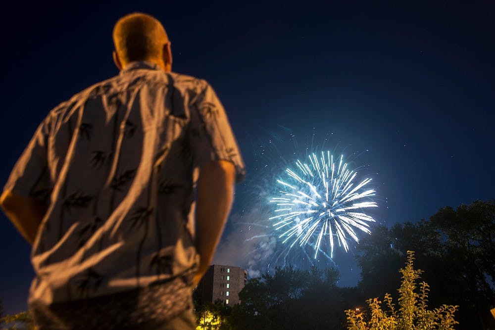 <p>Dewitt, Mich., resident Steve Miner watches fireworks July 4, 2014, at Adado Riverfront Park in Lansing. Many residents gathered at the park to watch live entertainment and see fireworks. Corey Damocles/The State News</p>