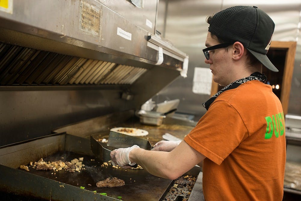 <p>East Lansing resident and Menna's Joint manager Isaac Sprague prepares an order of the Master Dub sandwich for a customer Jan. 14, 2015, at Menna's Joint, 115 Albert Ave. in East Lansing. Emily Nagle/The State News</p>