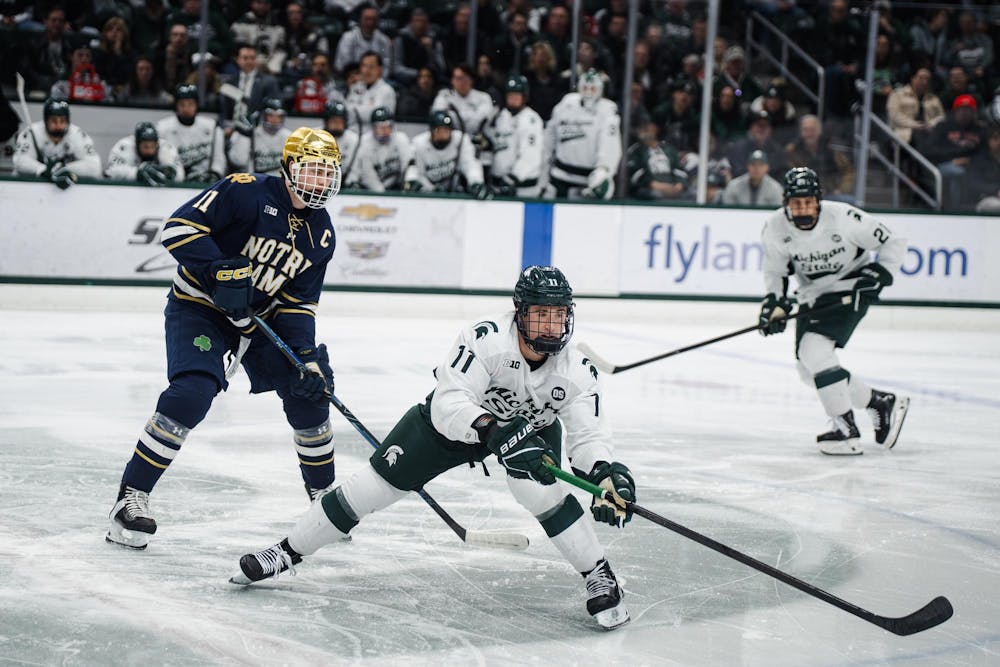 Notre Dame junior Danny Nelson (11), Michigan State sophomore Owen West (11) and Michigan State freshman Anthony Romani (21) reaching for the puck during a game at Munn Ice Arena in East Lansing, Michigan, on Friday, Feb. 20, 2026.