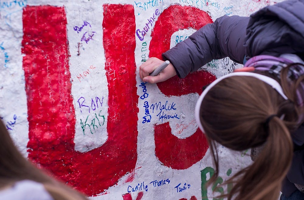 <p>Freshman education Geordan Bader makes the pledge to stand against sexual assault Nov. 17, 2014, at the rock on Farm Lane. Phi Kappa Psi asked people to sign their names on the rock as a way to bring awareness to the "It's On Us" campaign against sexual assault. Erin Hampton/The State News</p>