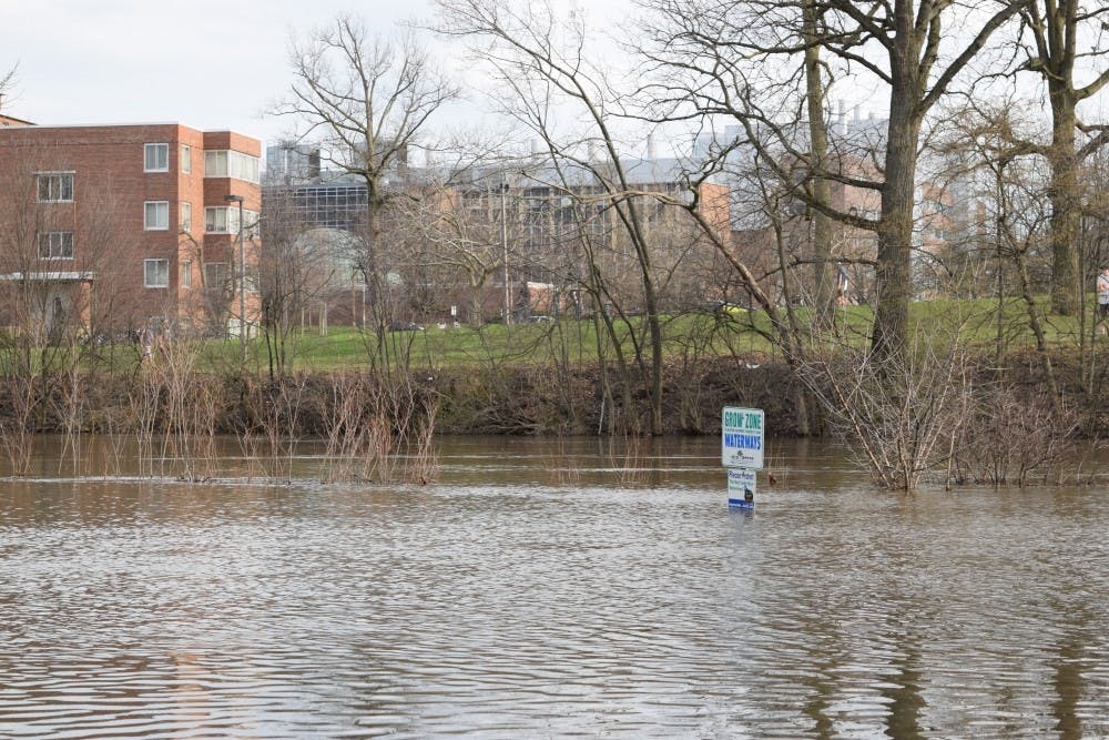 Flooding engulfs a sign along the river trail that runs past Shaw Hall and under Farm Lane on April 9, 2017.

