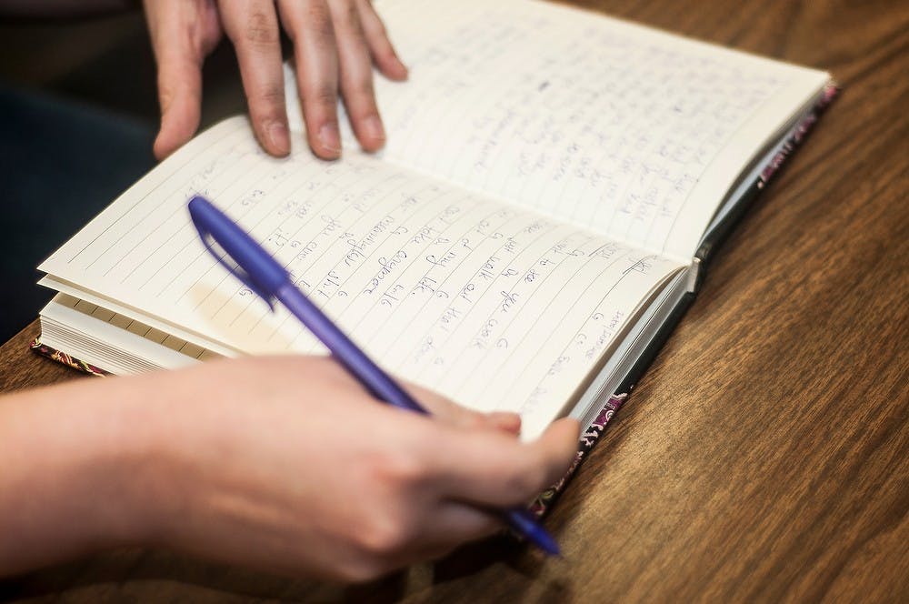 	<p>Animal science sophomore Jeanette Cortese writes lyrics in her notebook for a song her and her bandmate, genetics and psychology sophomore Megan O&#8217;Donovan are working on Feb. 7, 2014, during a Guitar Club jam session in Holmes Hall. Cortese and O&#8217;Donovan&#8217;s band is called the Near Futures. Erin Hampton/The State News</p>