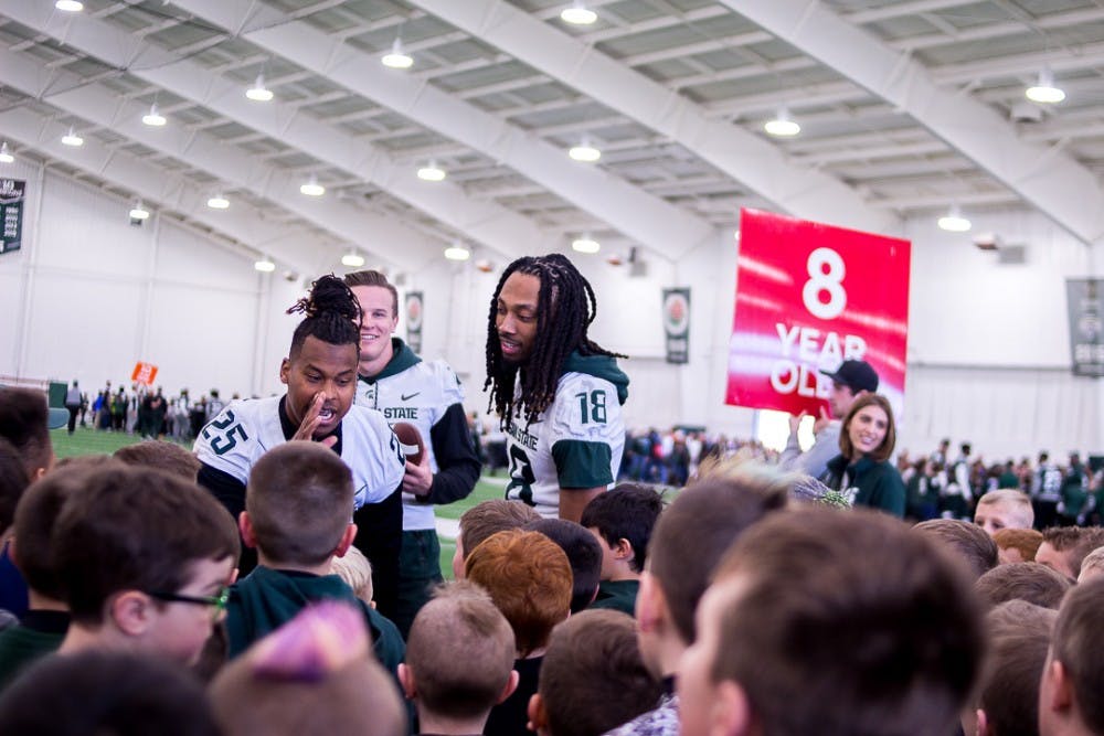<p>Junior wide receiver Darryl Stewart Jr. (25) and senior wide receiver Felton Davis III (18) teach the kids a chant during the youth clinic before the spring football game on April 7, 2018 at Duffy Daugherty Football Building.</p>