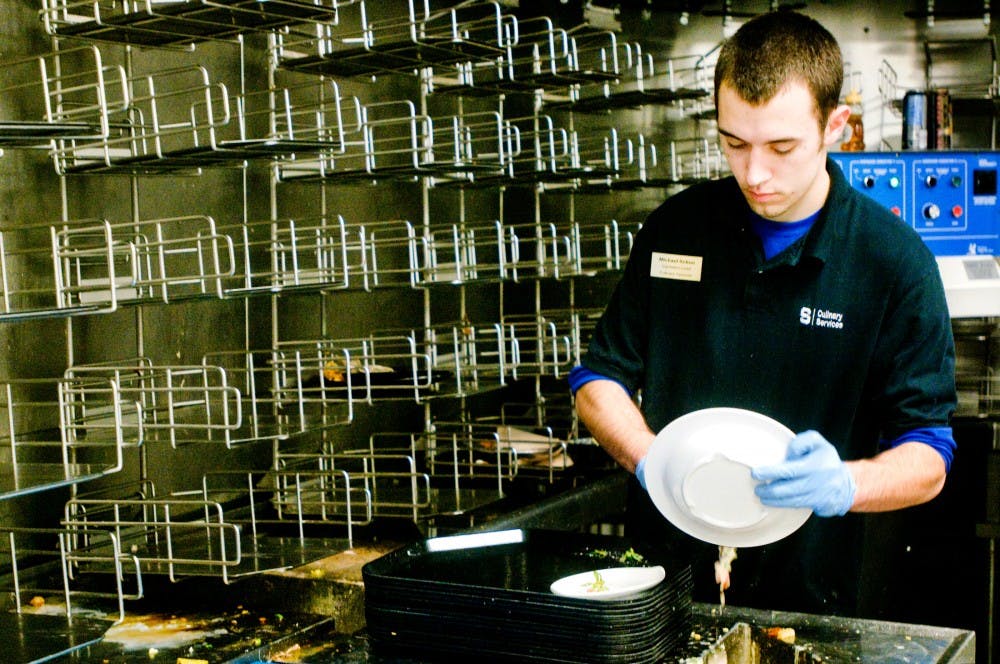 Special education freshman Michael Schon scrapes uneaten food off of a plate Wednesday afternoon while working in the dish room of Brody Square. Samantha Radecki/The State News