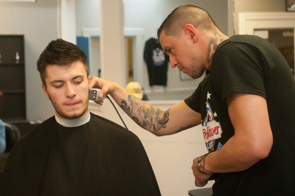 Finance sophomore Jack Viazanko , left, gets a hair cut by shop manager Jesse Medina on April 12, 2016 at Grand River Barber Company at 201 E. Grand River Ave.  