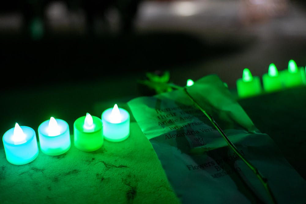 <p>A paper reading "Remember their names: Arielle Anderson, Brian Fraser, Alexandria Verner" lies in between a row of green-lit candles on Feb. 13, 2024. One year after the Michigan State University campus shooting, a remembrance ceremony was held to remember and reflect on the tragedy.</p>