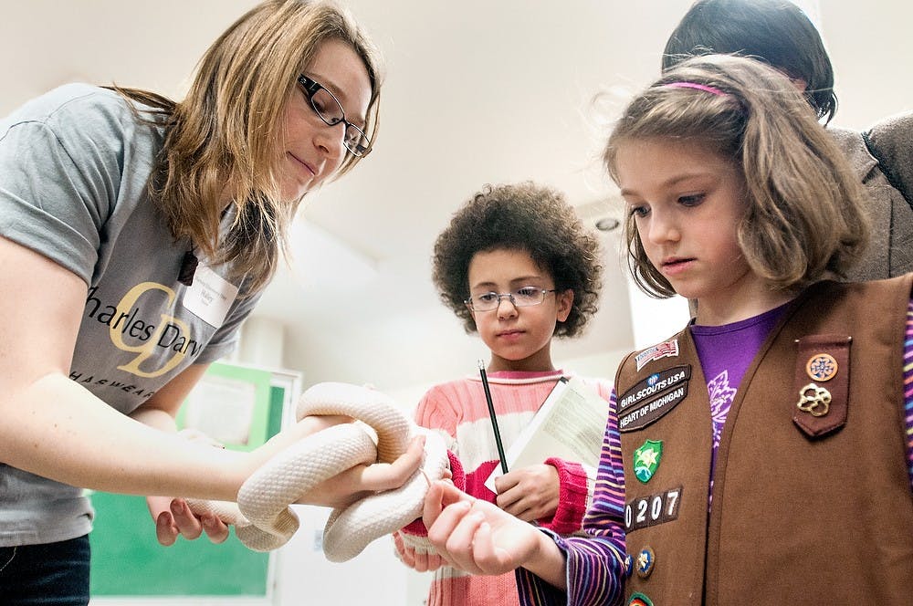 	<p>Darwin Day volunteer Hayley Sisson holds an albino Texas rat snake in front of Lansing residents 7-year-old Gwenyvaer Kofoed, right, and 8-year-old Madison McKinstry on Feb. 10, 2013, during Darwin Day at the <span class="caps">MSU</span> Museum. Live snakes and other reptiles were shown off at the event. </p>