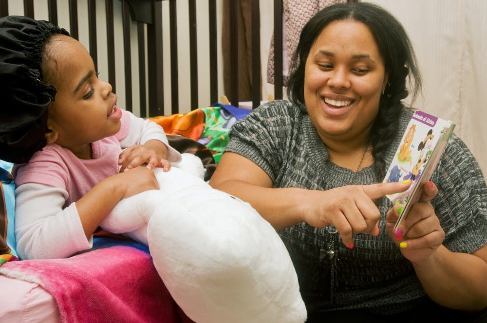 Social work senior Natalie Kyles laughs as she reads to her daughter Kadence, 3, Wednesday night before Kadence went to sleep. Kyles is looking forward to graduating so she can assist youth at risk with her social work degree. Anthony Thibodeau/The State News