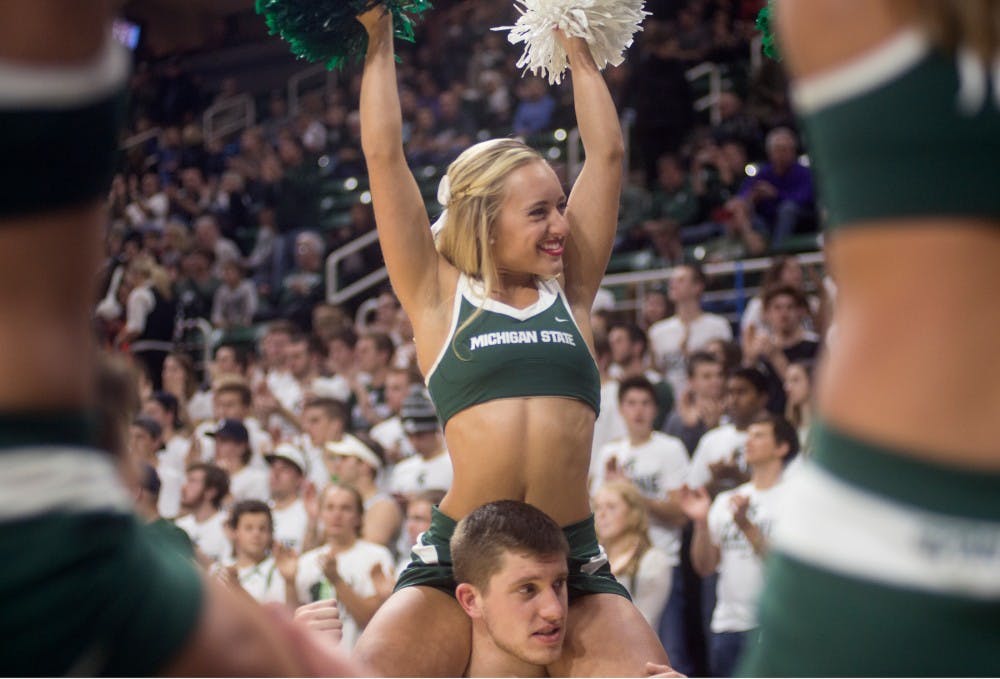 <p>Advertising sophomore Olivia Valley cheers while biochemistry senior Sam Vaitkevicius holds her up during the men's basketball game against Arkansas-Pine Bluff on Nov. 20, 2015 at Breslin Center. The cheerleading squad attends and participates in numerous sporting events around campus. </p>