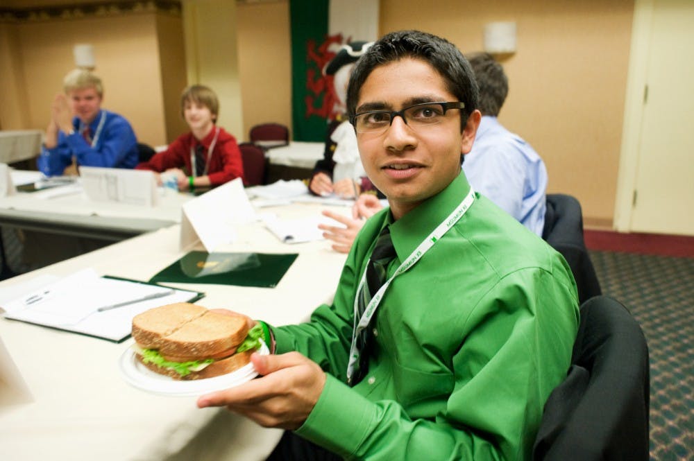 Shiva Metha, 15, of North Farmington High School in Farmington Hills, Mich, who played as Lord Sandwich during the mock session of British Parliament, receives a sandwich from the hands of international relations sophomore Kristopher Wilson. The modern-day meal with two slices of bread and fillings in between is named after John Montagu, 4th Earl of Sandwich. Sponsored by the MSU Model UN club, the 3-day event had around 600 students in attendance. Justin Wan/The State News