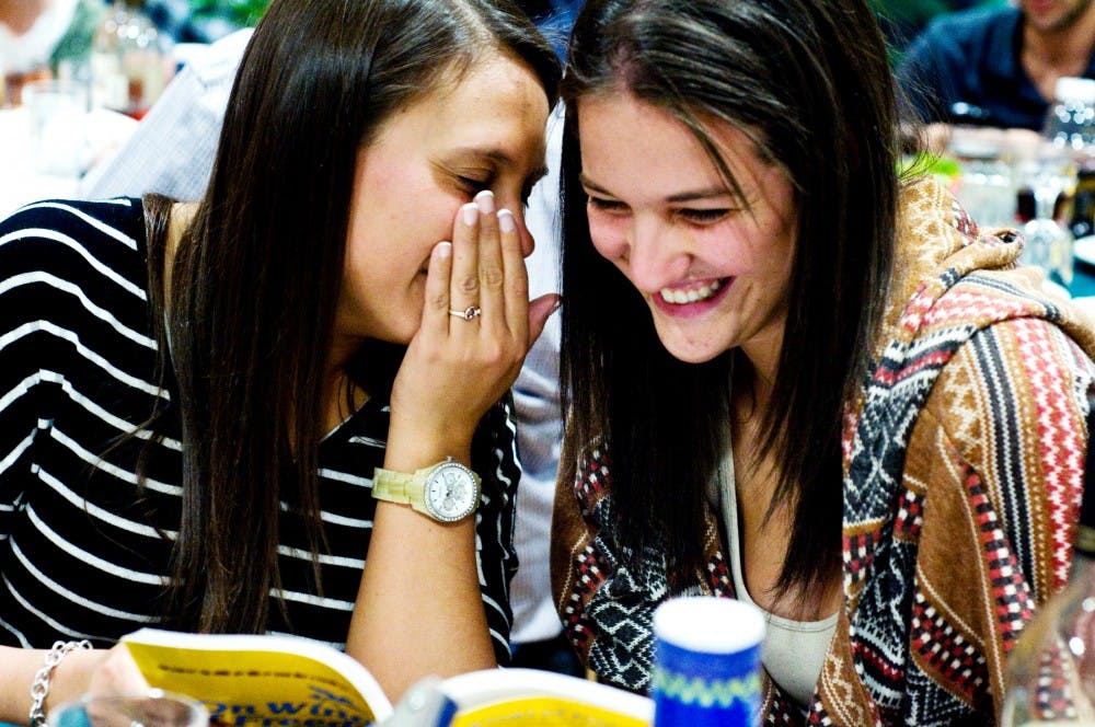 	<p>James Madison senior Whitney LeMieux whispers in the ear of hospitality business sophomore Rachel Rosenberg as they read out of the Haggadah Tuesday evening at <span class="caps">MSU</span> Hillel. </p>