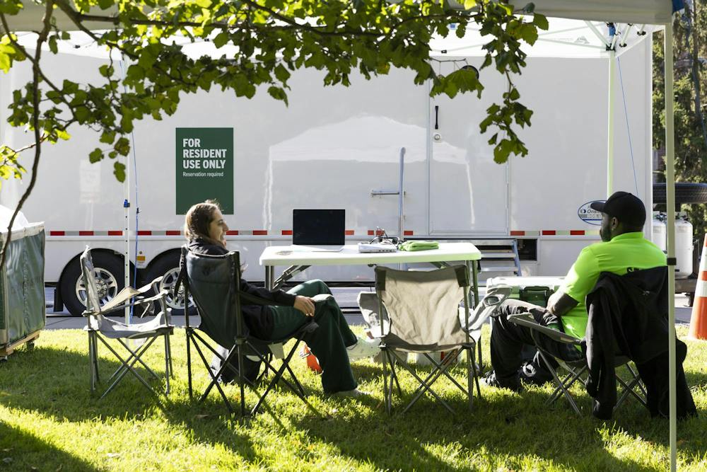 <p>Michigan State Mobile Shower unit Coordinator Ava Leonardis (left) and Centurion Security guard, Micah Rembert (right) sit and wait to assist students to check in for their shower times at the mobile shower units brought on campus in East Lansing, Mich., on Thursday, Sept. 24, 2026.</p>