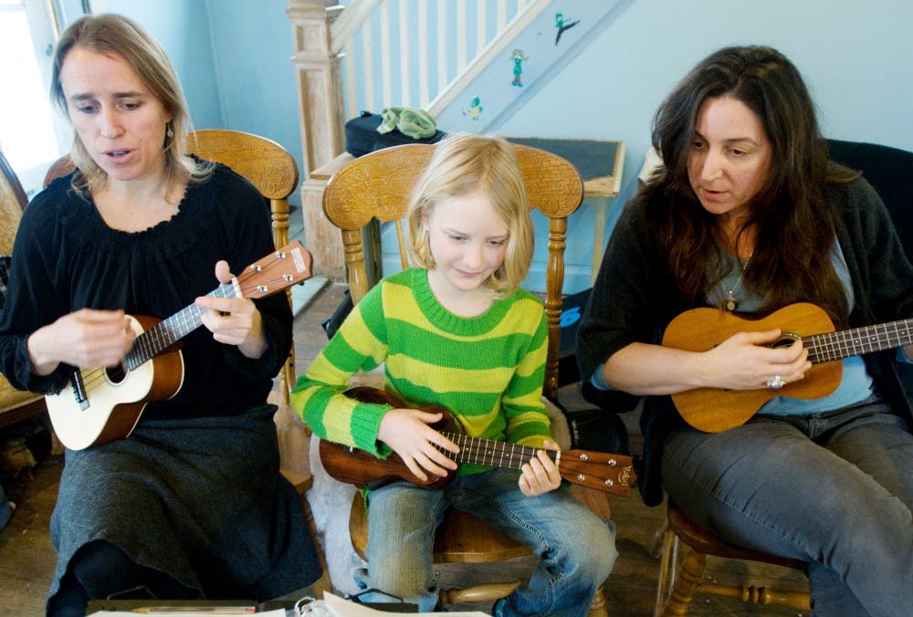 From left, Onondaga resident Chela Ashley and her daughter, Brigid Ashley-Grose, 10, and Lansing resident Petra Daher play a song on their ukuleles Thursday at a friend's home in Lansing. All three are part of a small group of enthusiasts that call themselves Ukulele Ladies. Kat Petersen/The State News