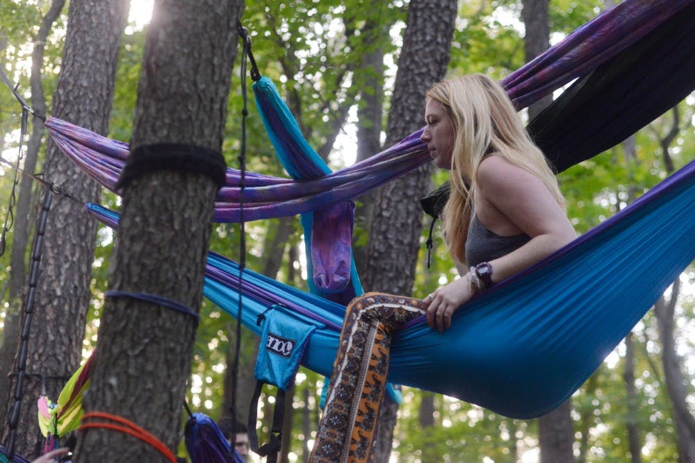 <p>Advertising junior Hannah Tizedes works on tying hammocks to trees on Oct. 7, 2015, at the Fenner Nature Center, 2020 Mt. Hope Ave., in Lansing. The MSU Hammocking Club attempted to break the Guinness World Record for most consecutively stacked hammocks, but was shut down by park authorities. </p>