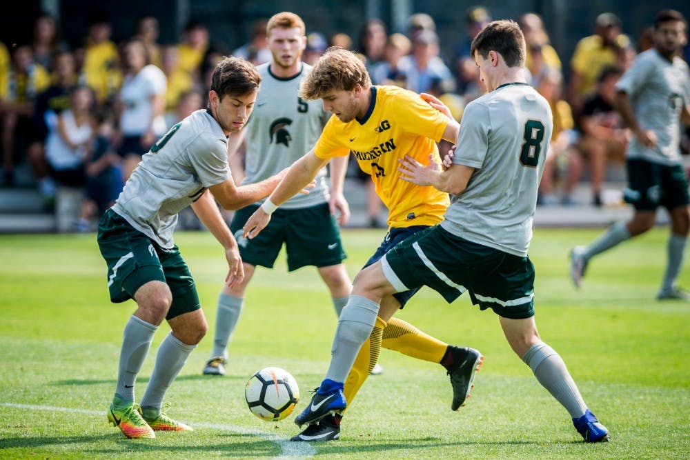 Sophomore midfielder Giuseppe Barone (10) and senior defender Brad Centala (8) attempt to take the ball from Michigan forward Jack Hallahan (11) during the game against the University of Michigan on Sept. 17, 2017 at U-M Soccer Stadium. The Spartans defeated the Wolverines, 1-0.