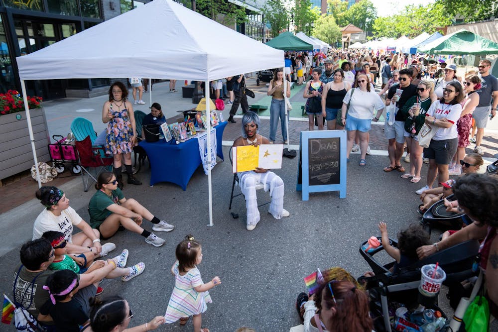 <p>Drag performer Aurora Manifesto reads a self-made book to attendees during East Lansing Pride on Albert Ave in East Lansing, Mich., on June 13, 2026.</p>
