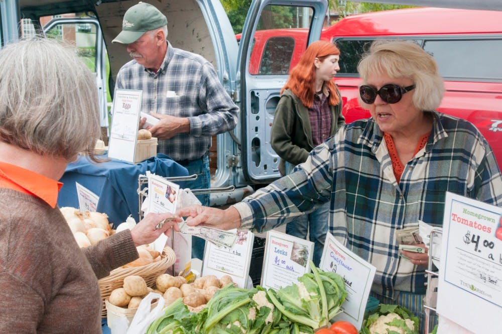 Okemos, Mich. resident Lauree Roney, left, purchases vegetables from Titus Farms owner Rose Titus on Sept. 21, 2014, at the East Lansing Farmers Market. 