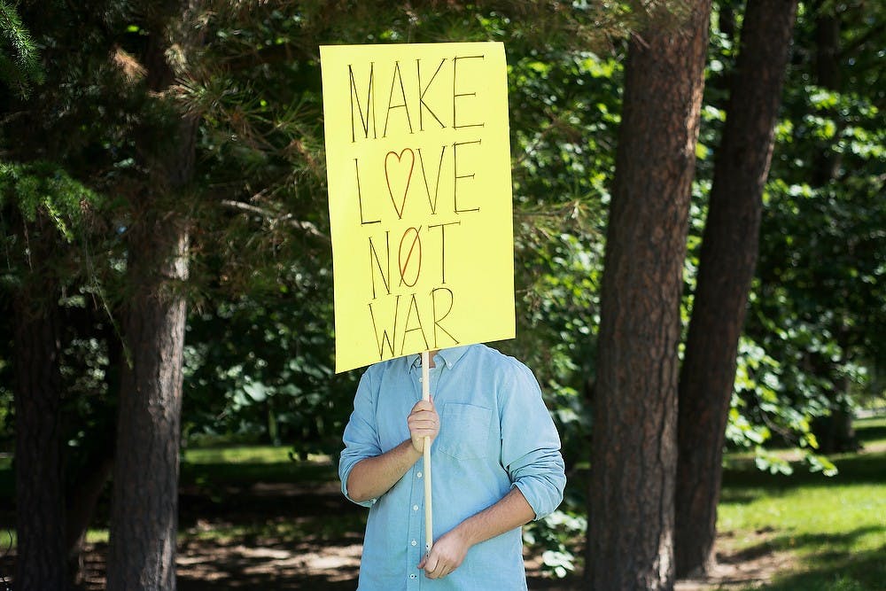 	<p>Daniel Katz, philosophy and sociology of science and religious studies junior, holds a &#8220;Make Love Not War&#8221; sign Sept. 3, 2013, outside Wells Hall. The Michigan State College Libertarians and the Young Democratic Socialist Organization joined together outside Wells Hall to spread awareness about potential military action in Syria. Julia Nagy/The State News </p>