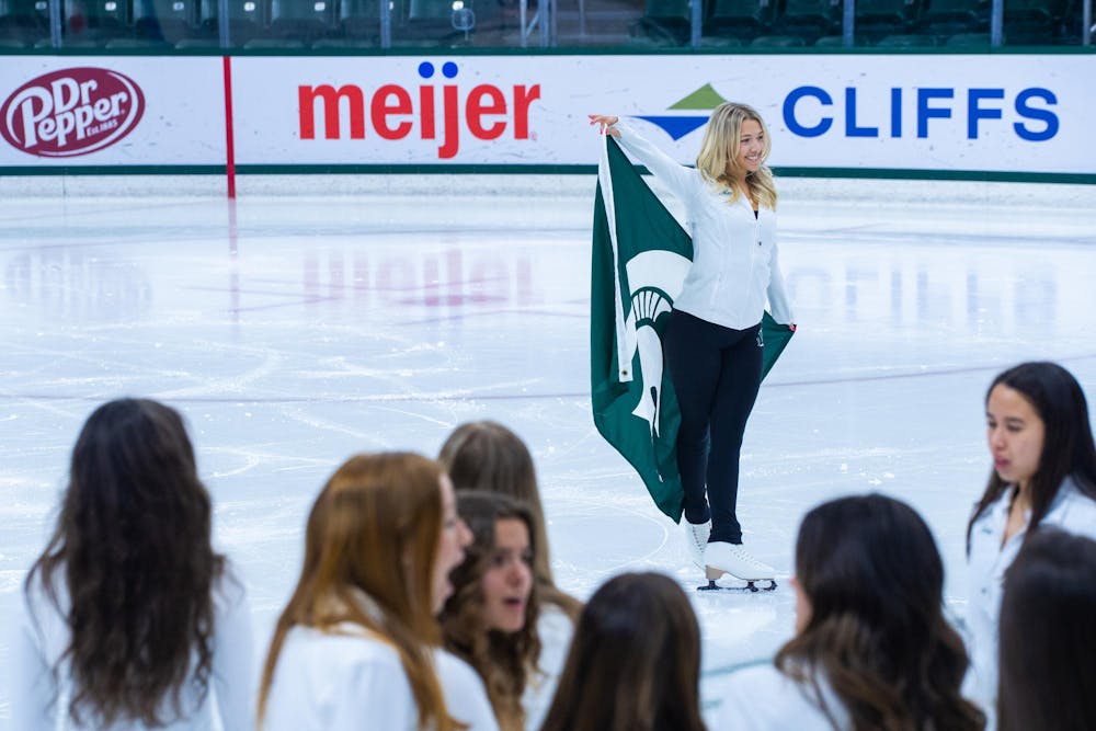 A member of the MSU Figure Skating Team poses for a portrait with a Spartan flag at Munn Ice Arena on March 22, 2024.