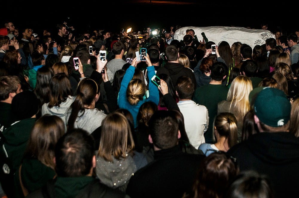 <p>Students stand and listen to men's basketball head coach Tom Izzo at the Rock on Farm Lane on April 9, 2014, in remembrance of Lacey Holsworth at her memorial. Holsworth was a good friend of senior forward Adreian Payne and passed away April 8 after a battle with cancer. Erin Hampton/The State News</p>