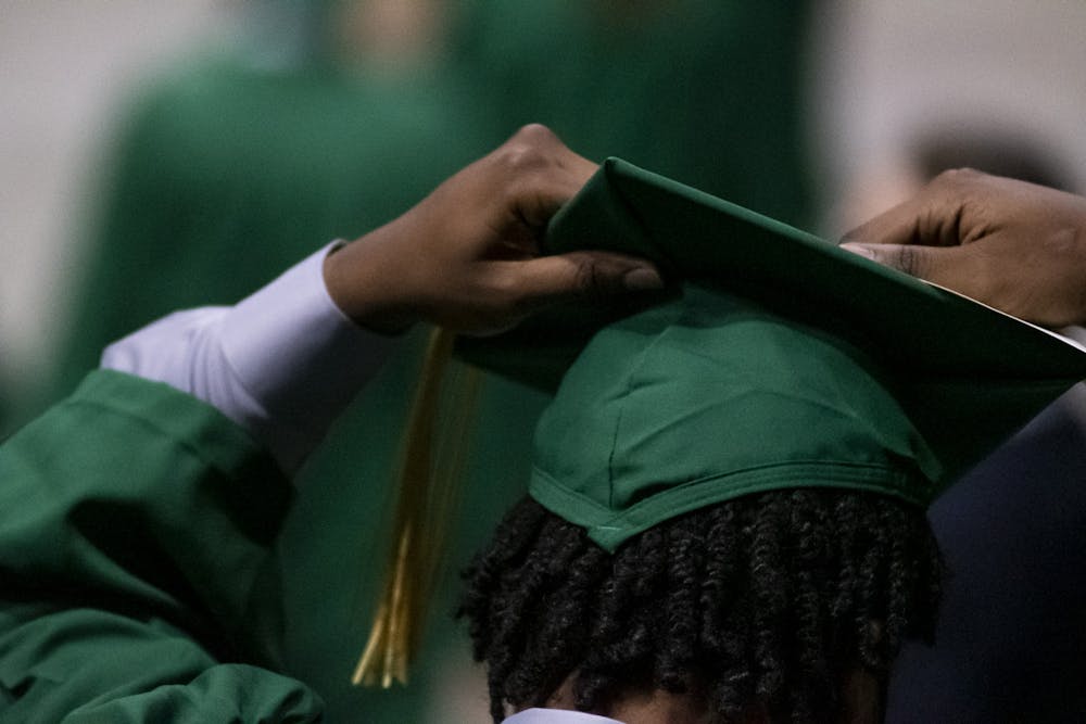 <p>A baccalaureate graduate fixing their tassel at the 2020 graduate and spring and summer 2021 graduate commencement ceremony at the Breslin Center on Sept. 18, 2021.</p>