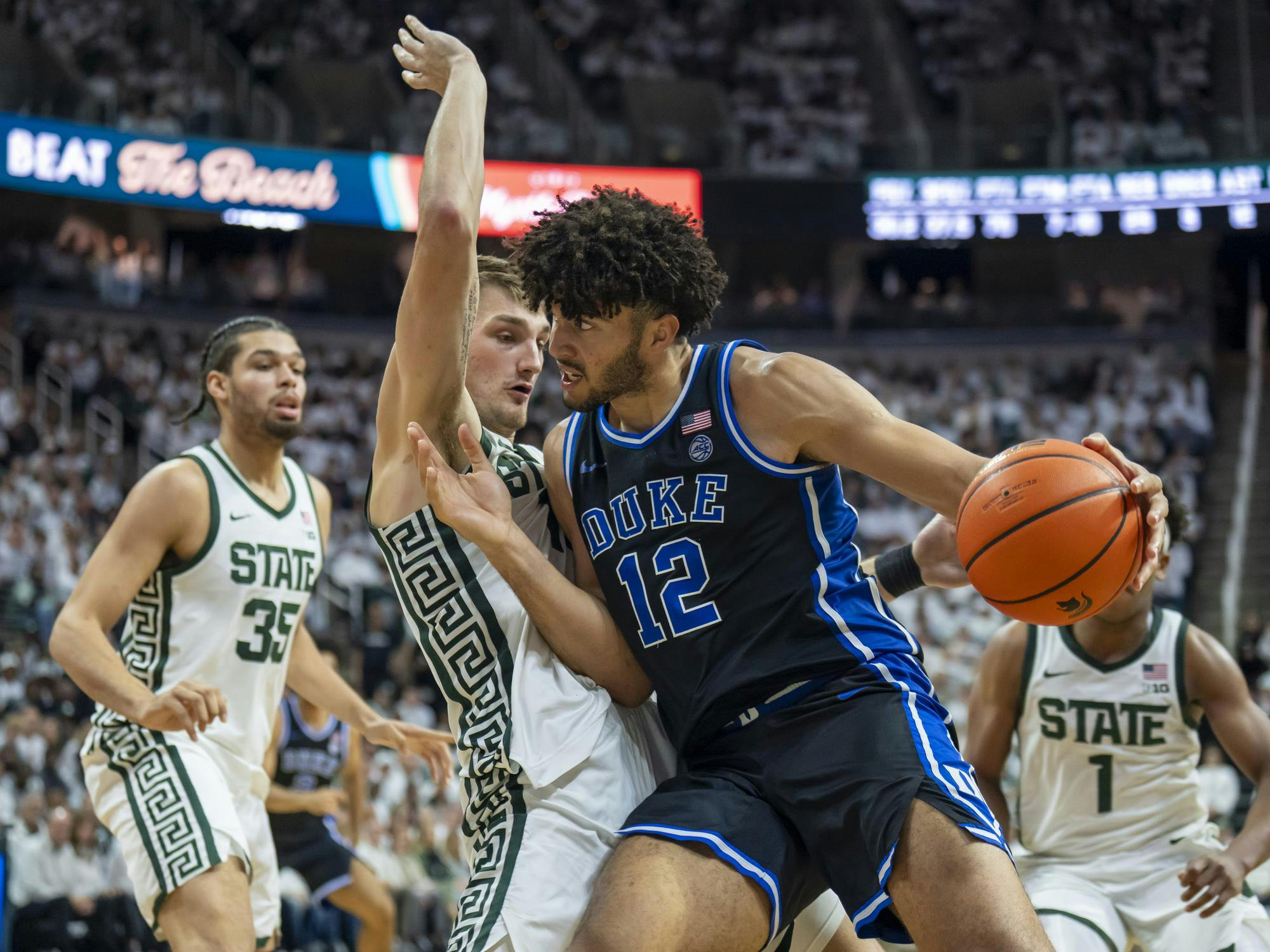 Michigan State senior center Carson Cooper (15) defends the net from Duke's freshman forward Cameron Boozer (12) at the Breslin Center in East Lansing, Michigan on Saturday, Dec. 6, 2025. 