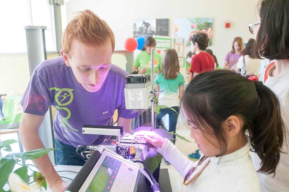 <p>Biochemistry and nueroscience senior Chris Porzondek teaches Okemos resident Sarah Shim, 9, about photosynthesis April 18, 2015, during the MSU Science Festival in the Chemistry building. Porzondek is a member of the Plant Biology Club which had an educational booth at the event. Kelsey Feldpausch/The State News</p>