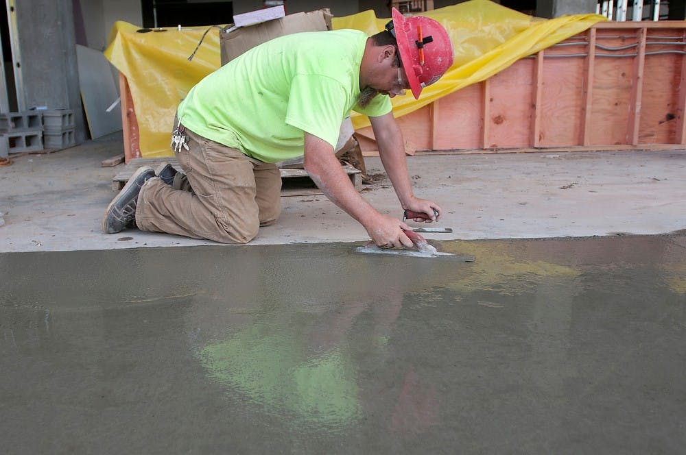 	<p>Grand Rapids resident Jared Veale smooths out concrete on July 24, 2013, at HopCat bar and restaurant, 211 Ann St. Construction is expected to finish in late August. Weston Brooks/The State News</p>