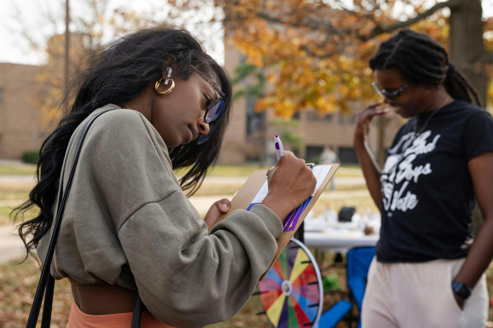 A MSU student writes down what issues regarding voting are important to her during the Voices of Power Black Voter Rally at Oyer Lawn on Oct. 30, 2024. The Black Student's Alliance's Voices of Power Rally was held to spread the importance of voting and civic engagement including a live DJ, free food, student speakers, free merch and more.