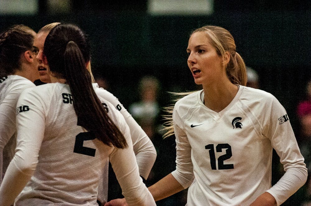 Senior setter Rachel Minarick (12) reacts with teammates to a play during the game on Nov. 1, 2017 at Jenison Fieldhouse. The Spartans fell to the Nittany Lions 3-1. 