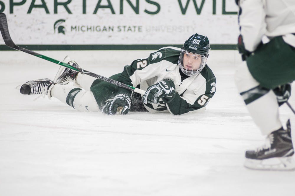Sophomore defenseman Mitch Eliot (52) watches the puck after taking a hit during the game against Minnesota on Jan. 18, 2018 at Munn Ice Arena. The Spartans fell to the Gophers 5-4. 
