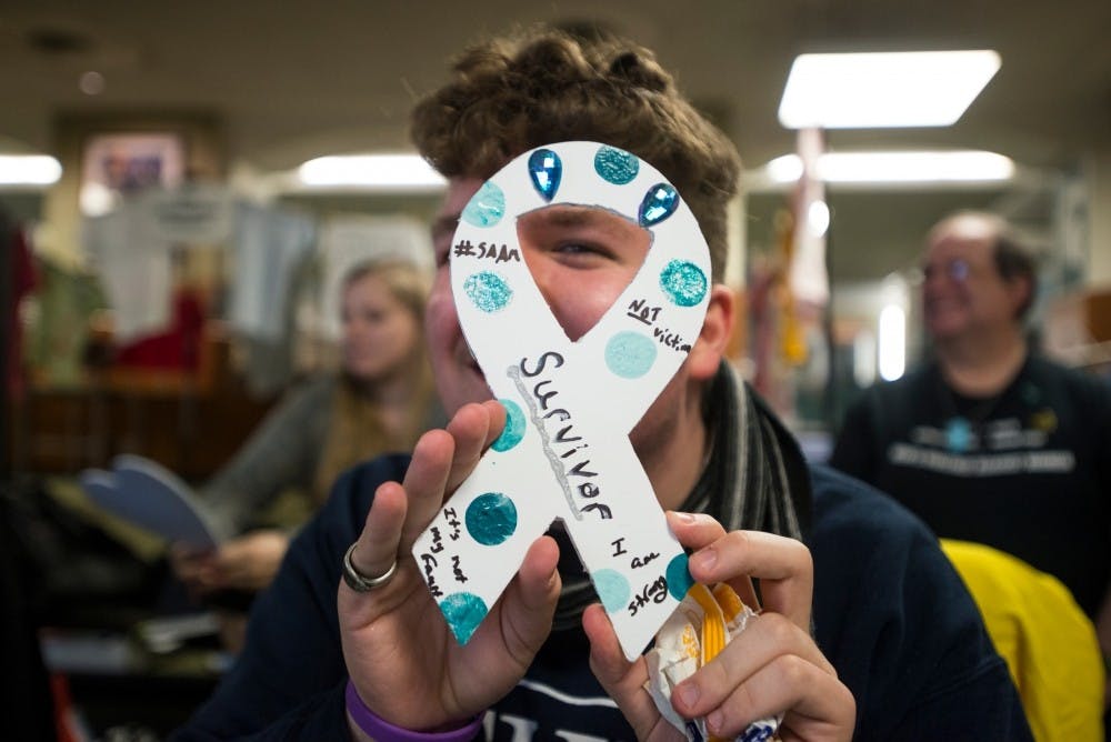 Social work junior Ian Jacobs holds a craft for Take Back The Night on April 7, 2016 at the Union. Take Back The Night is an event dedicated to ending sexual assault and domestic violence through spreading awareness. (Nic Antaya | The State News)
