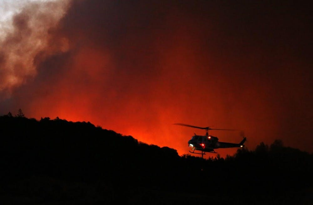 A helicopter prepares to drop water on a fire threatening the Oakmont community along Highway 12 in Santa Rosa, Calif. on Oct. 13. Photo: Genaro Molina/Los Angeles Times/TNS