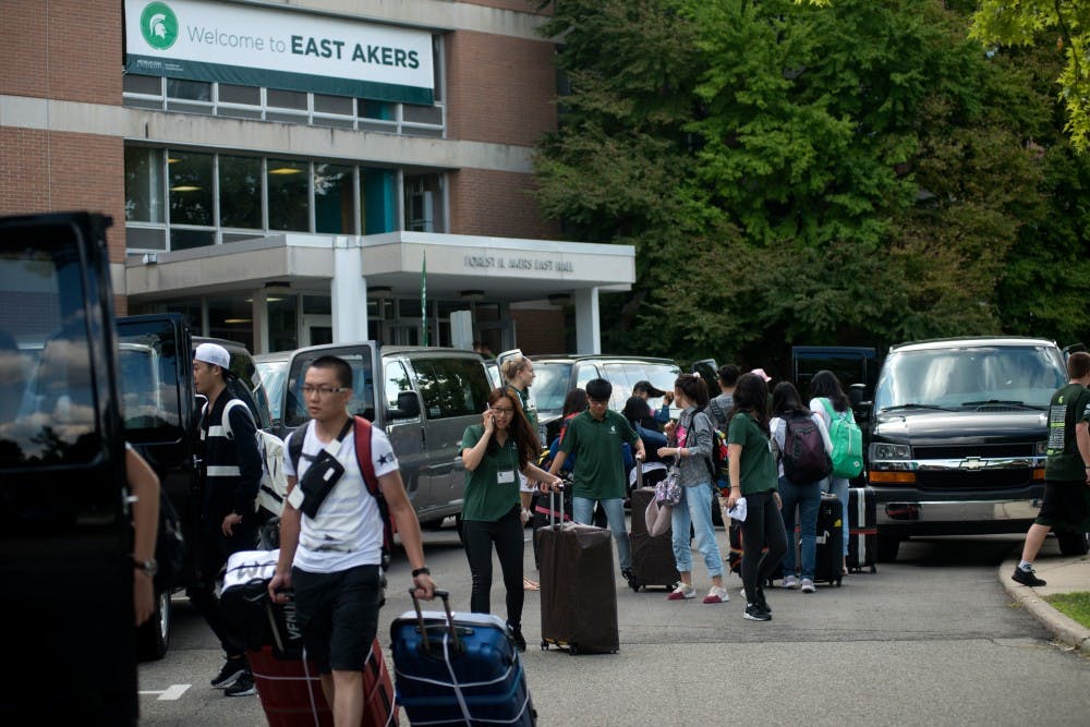 <p>International students make their way to different shuttles on Aug. 22, 2015, in front of Akers Hall. International move-in consisted of multiple Michigan Flyer buses dropping students off from the Detroit Metropolitan Wayne County Airport to Akers Hall. Students were then shuttled to their individual dorms. Julia Nagy/The State News</p>